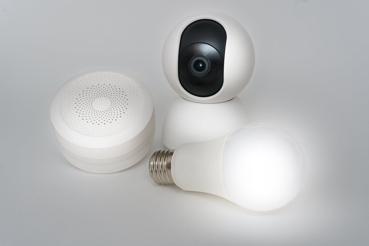 A set of smart home devices including a camera, speaker, and lightbulb on a white background.